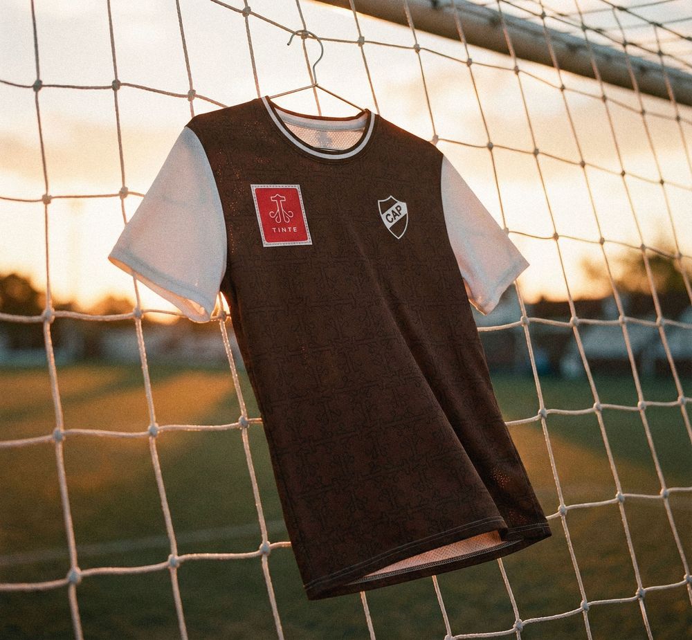 Camiseta colgada en la red de una portería al atardecer